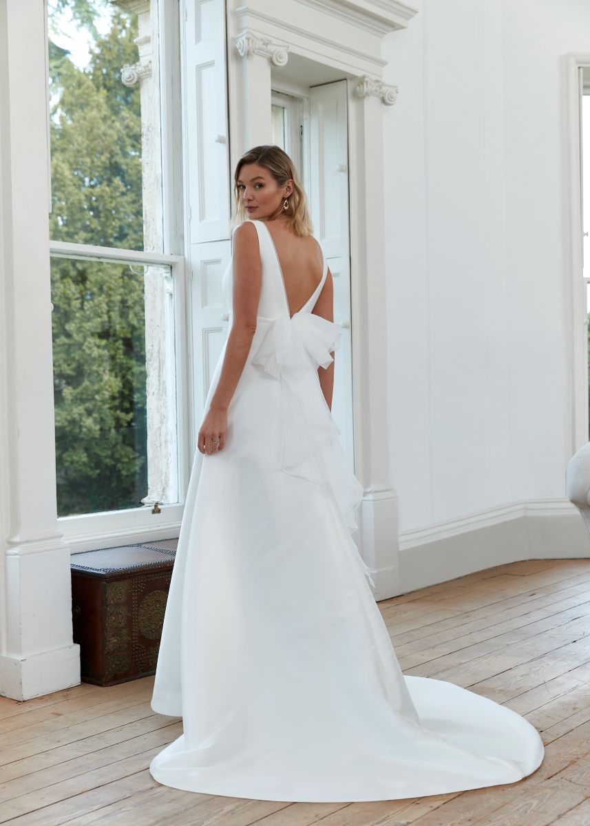 Romantica of Devon Dawn wedding dress back angle highlighting detachable organza bow and satin ballgown train