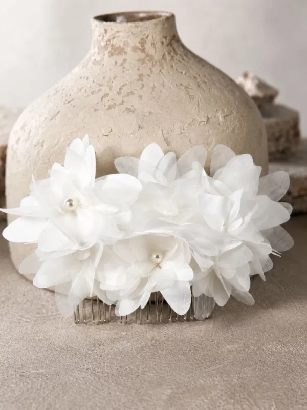 Close-up of CP406 satin and organza flower comb with pearl centres on rock