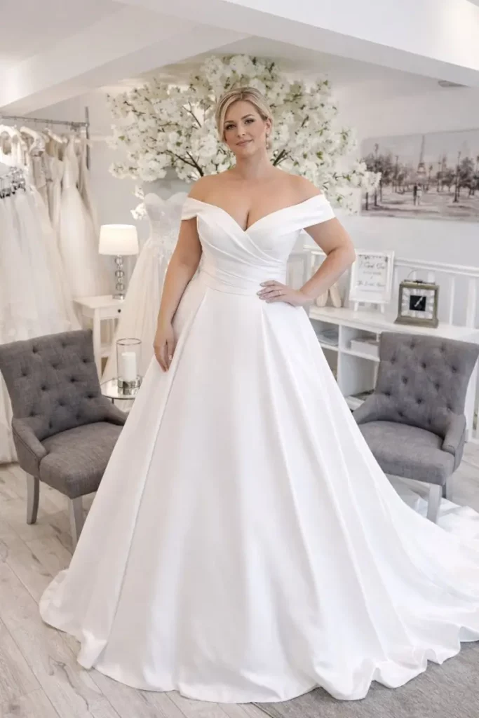 Off-the-shoulder wedding dress in smooth satin fabric at The Bridal Affair