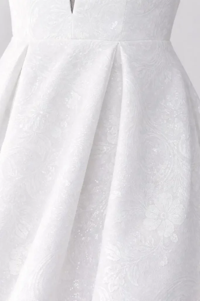 Close-up of textured wedding dress fabric with pleated skirt detail