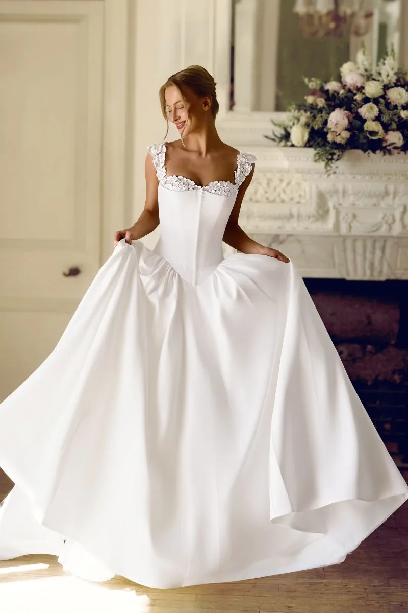 Elara by Phoenix Gowns romantic ivory satin ballgown with floral lace neckline, fitted basque bodice and flowing skirt.