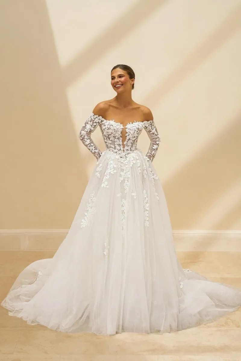 Emmaline by Danielle Couture ivory off-the-shoulder ballgown wedding dress with long illusion lace sleeves, plunging neckline and full tulle skirt.